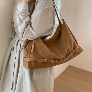 Detail of a large brown faux suede hobo bag with buckled leather strap detail