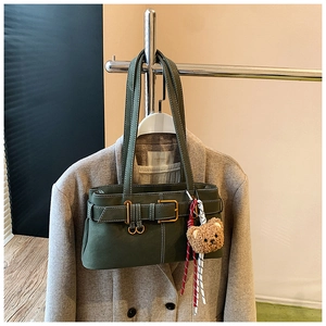 Detail of olive green leather bag with decorative buckle and plush bear charm