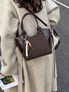 Sac seau marron avec pendentif en perles porté avec un élégant manteau en laine
