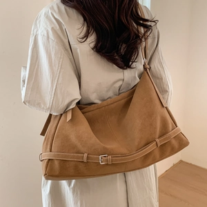 Detailed back view of a large camel suede tote bag worn by a model in a minimal room