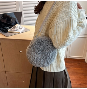 Close-up of gray faux fur round crossbody bag with silver hardware in a warm lifestyle setting