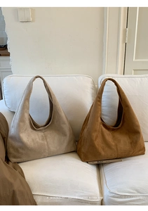 Détail de sacs fourre-tout en daim minimalistes en kaki et marron sur canapé