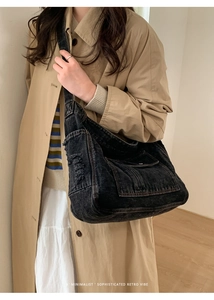Detail of vintage washed black denim crossbody bag with large capacity on model