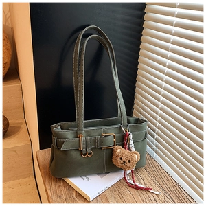 Detail shot of olive green shoulder bag with golden buckle and plush bear pendant
