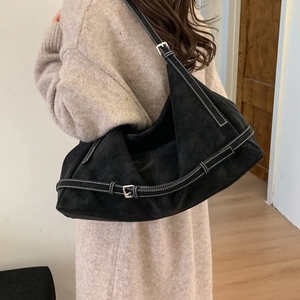 Detail of black tote bag showing white contrast stitching and silver adjustable buckle strap