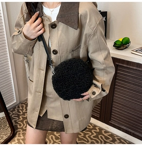 Detail view of round black plush crossbody bag made of faux lamb wool with a slim strap
