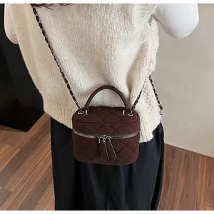 Close-up of brown suede vanity bag with quilted patterns and woven chain strap