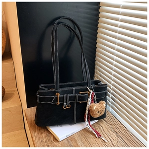 Detail of black leather shoulder bag with white stitching, metal buckle and plush charm