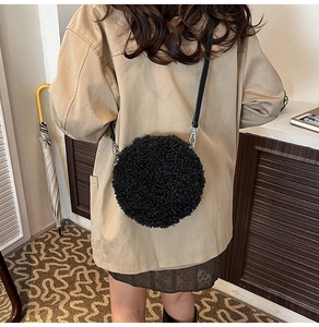 Close-up of black sherpa round crossbody bag with leather strap worn by a model