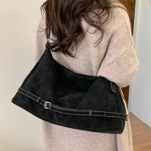 Detail of black suede tote bag with white contrast stitching and decorative buckle strap