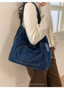 Detail of vintage dark blue denim tote bag with distressed edges and adjustable strap