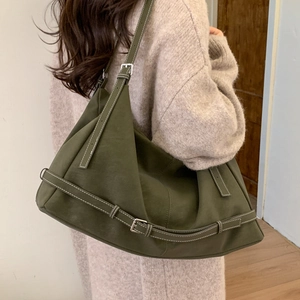 Detail of dark green leather tote bag with white stitching and silver metal buckle