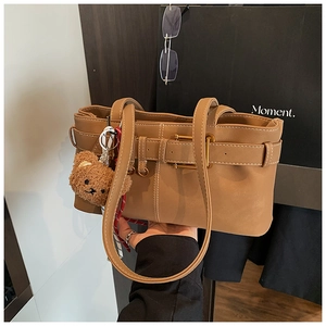 Brown vintage shoulder bag with decorative belt buckle and plush bear charm