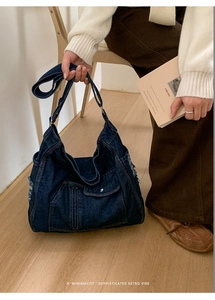 Close-up of retro blue denim tote bag featuring frayed edges and functional utility pockets