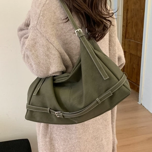 Detailed view of an olive green tote bag with white contrast stitching and buckle straps