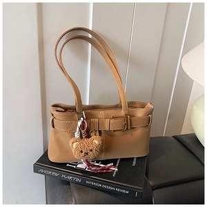 Detail of khaki retro shoulder bag featuring a smooth faux leather finish and bear charm
