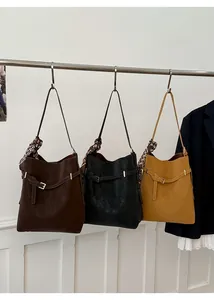 Three leather bucket bags in coffee, black, and yellow with silk scarf on handles