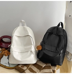 Detailed view of casual backpacks in cream and black colors with teddy bear charms