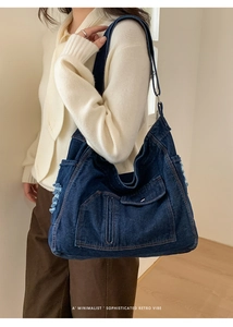 Detail of distressed denim tote bag featuring frayed edges and adjustable wide shoulder strap