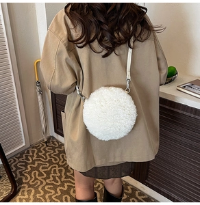 Back view of a model wearing a soft white lamb wool round crossbody bag with leather strap