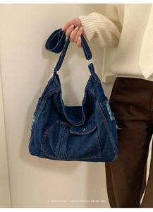 Detailed view of dark blue denim bag with distressed edges and vintage pocket design