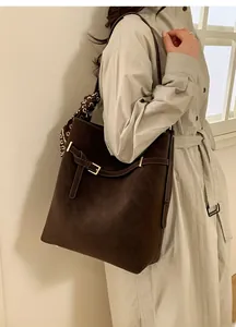 Detail of dark brown matte tote bag with gold hardware and decorative silk scarf accessory