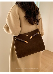 Détail du grand sac cabas en daim marron avec boucle dorée sur un manteau beige
