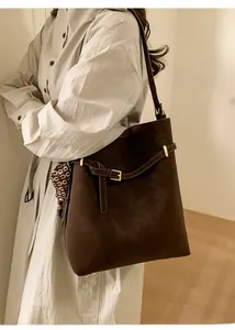 Detail of a brown leather tote bag with a decorative geometric silk scarf and gold hardware