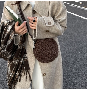 Detail of dark brown faux shearling round bag with slim shoulder strap on wool coat
