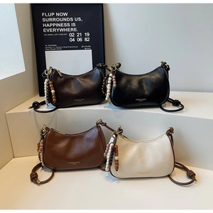 Detail of four half-moon underarm bags with wooden bead charms and knotted leather straps