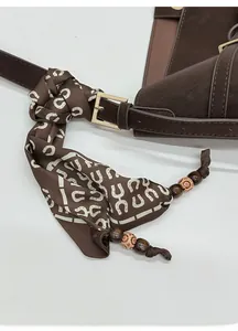 Detail of dark brown leather tote featuring a silk scarf with horseshoe patterns
