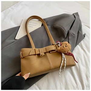 Detail of vintage brown shoulder bag with decorative belt buckle and cute bear charm