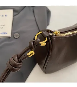 Detail of dark brown leather bag with knotted strap design and gold D-ring hardware