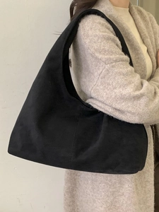 Sac hobo minimaliste en daim noir pour femme porté avec une tenue décontractée