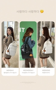 Detail view of stylish leather backpack featuring front zipper pocket and cute puppy charm