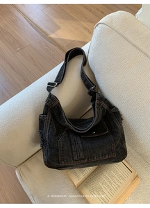 Close-up of black denim crossbody bag with contrast stitching and silver buckle detail