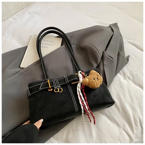 Detail of black underarm bag with white stitching and cute bear charm on a grey blazer
