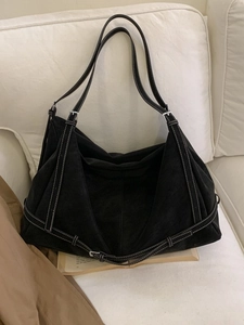 Black tote bag with white stitching detail, large capacity shoulder bag on white sofa