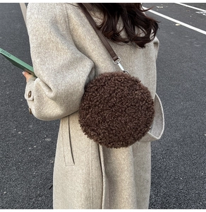 Outdoor model shot of a round brown teddy fleece crossbody bag with a leather strap