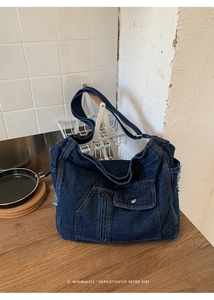 Detail of vintage blue denim shoulder bag showing pocket, zipper and frayed edges