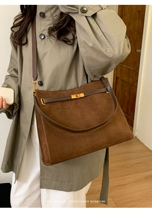 Gros plan d'un sac cabas en daim marron foncé avec fermoir doré et détails en cuir