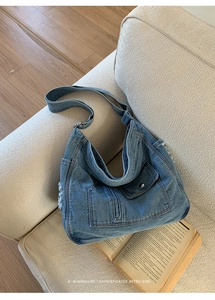 Detail of blue denim hobo bag featuring vintage frayed edges and side zipper pockets