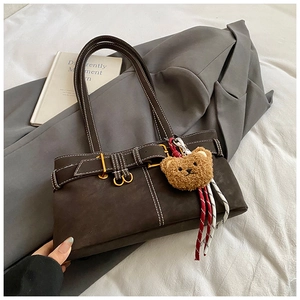 Detail of dark brown faux suede shoulder bag with contrast stitching and bear charm