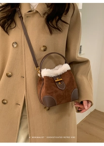 Détail du sac seau en daim marron avec bordure en fausse fourrure blanche et fermoir doré