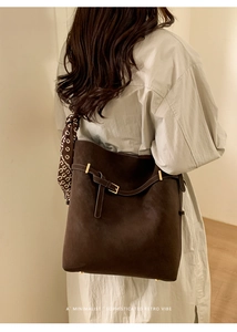 Detail of dark brown faux suede tote bag with decorative silk scarf and gold hardware