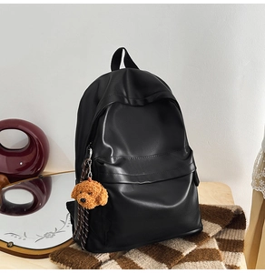Detail of minimalist black PU backpack with matte leather finish and cute puppy charm