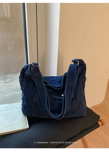 Close-up of deep blue denim tote bag with vintage brown contrast stitching and metal rings