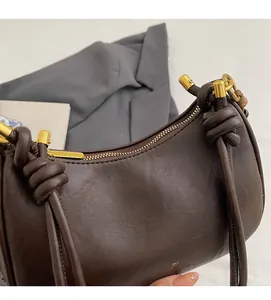 Close-up of soft brown leather texture with golden zipper and knot handle detail