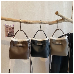 Detailed view of three faux fur bucket bags in brown, black, and gray on wooden hooks