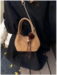 Détail du sac seau en suédine marron avec pompon en fourrure et chaîne dorée élégante